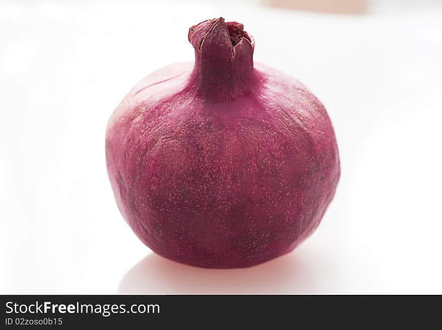 Fresh whole pomegranate on white table.