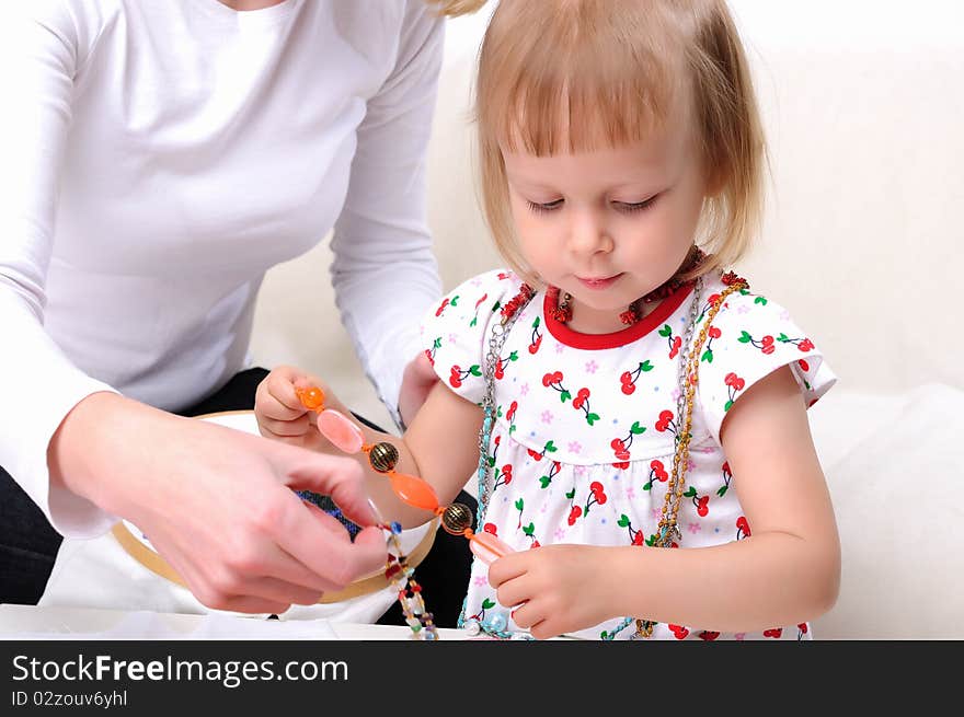 Young mother and her baby daughter spending time together. Dress up in costume jewelry.