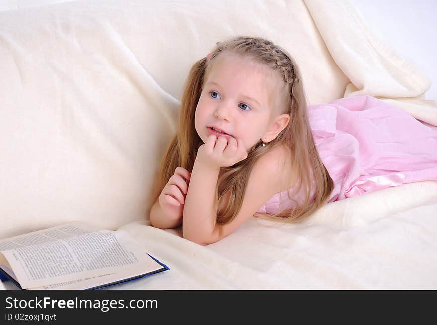 Little girl lying on the couch reading a book