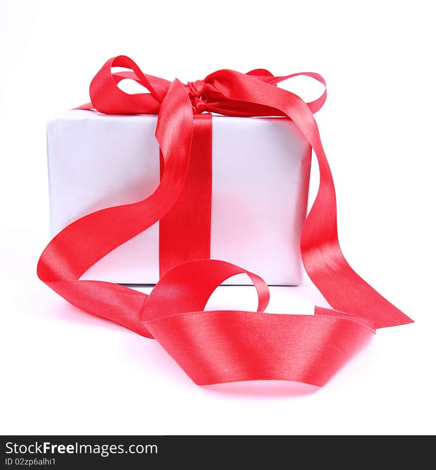 Gift in silver wrapping with a red bow on white background