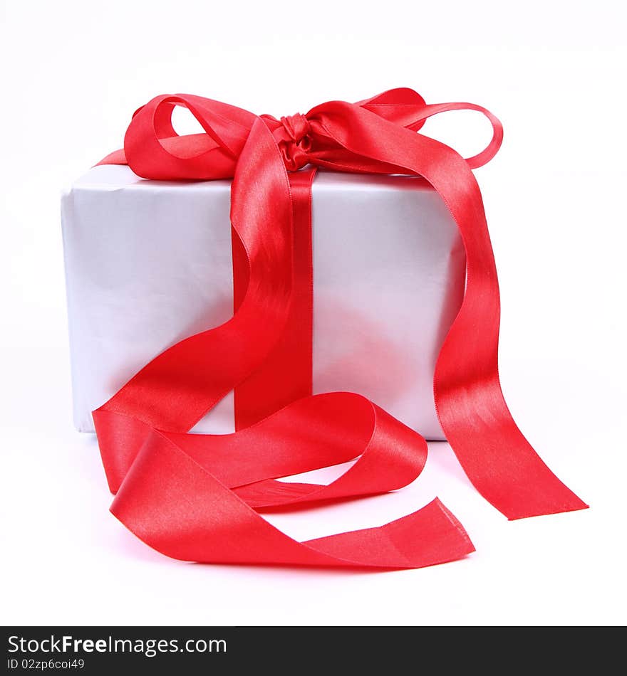 Gift in silver wrapping with a red bow on white background