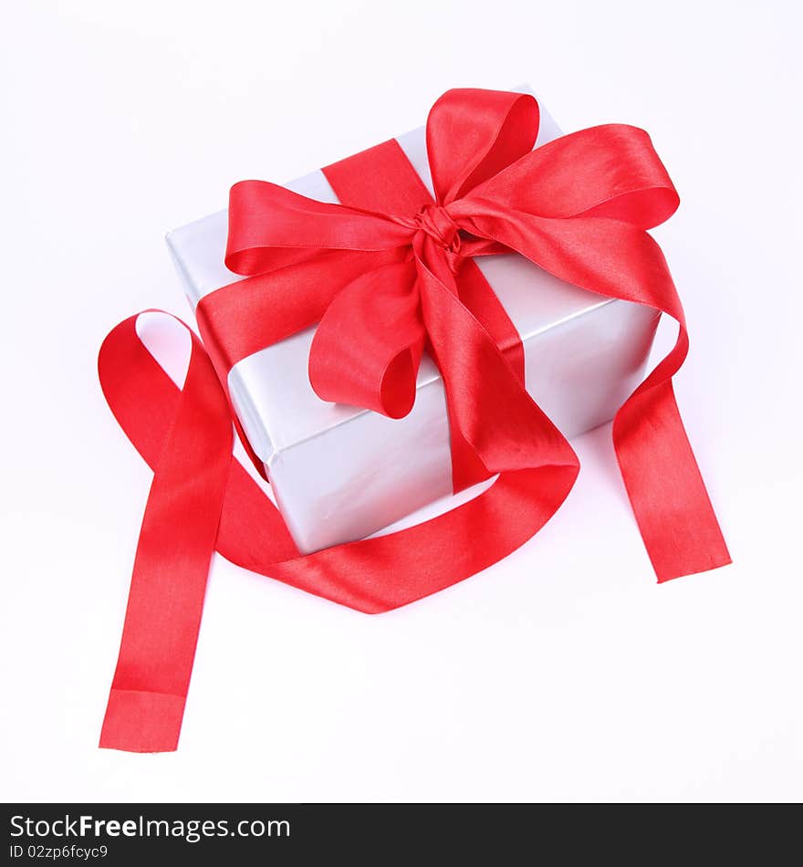 Gift in silver wrapping with a red bow on white background