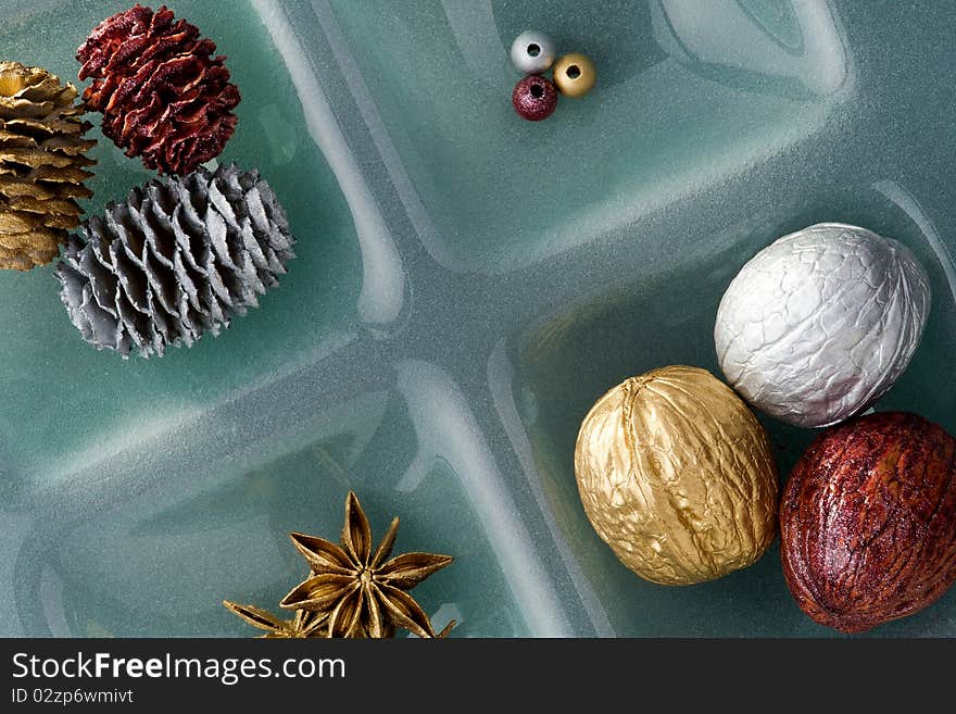 Christmas ornaments, golden and silver walnut and pine cone on glass plate. Christmas ornaments, golden and silver walnut and pine cone on glass plate.