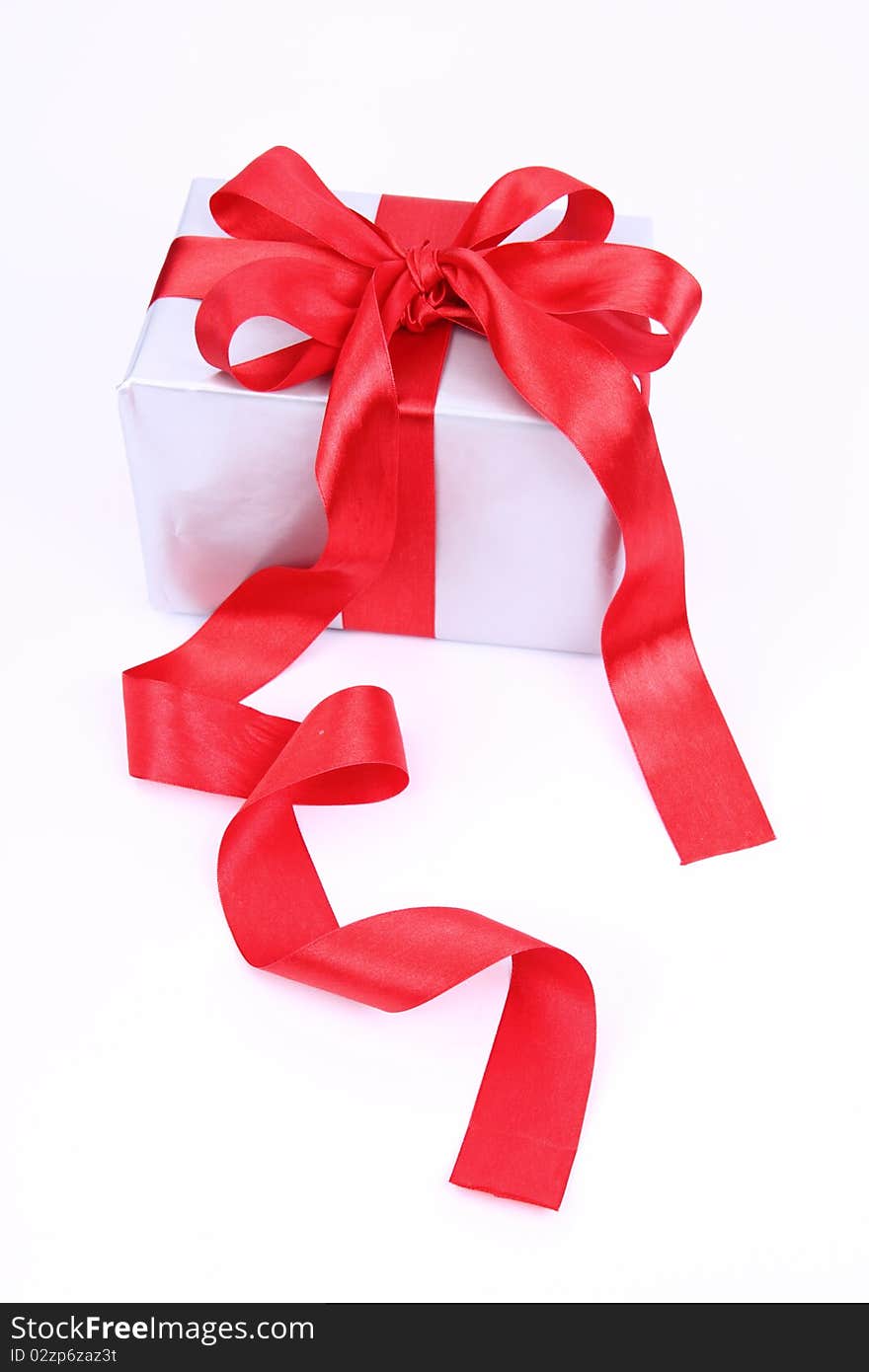 Gift in silver wrapping with a red bow on white background