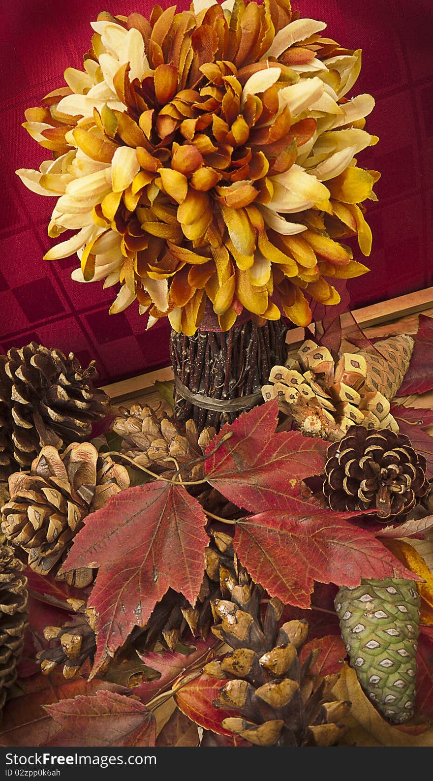 Fall still life with artificial flower arrangement and scattered pine cones and red maple leaves. Thanksgiving decoration. Fall still life with artificial flower arrangement and scattered pine cones and red maple leaves. Thanksgiving decoration.