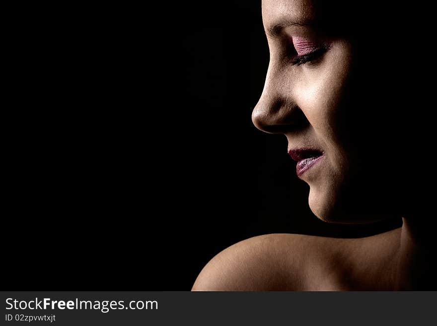 High contrast, closed eyes , head and one bare shoulder portrait of a young Indian female in dark background. High contrast, closed eyes , head and one bare shoulder portrait of a young Indian female in dark background