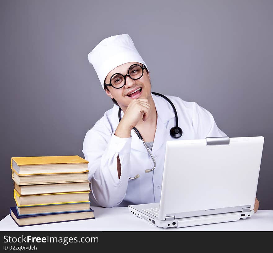 Young doctor with books and computer. Studio shot.