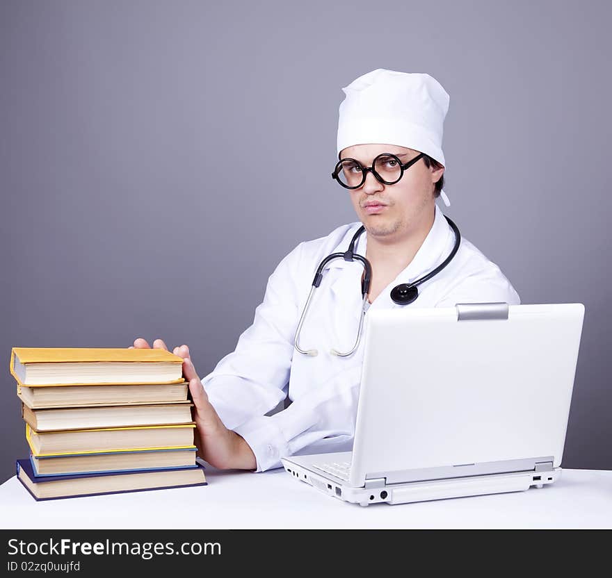 Young doctor with books and computer. Studio shot.