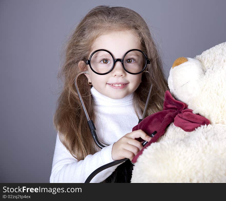 Little girl with  stethoscope and bear cub. Studio shot.