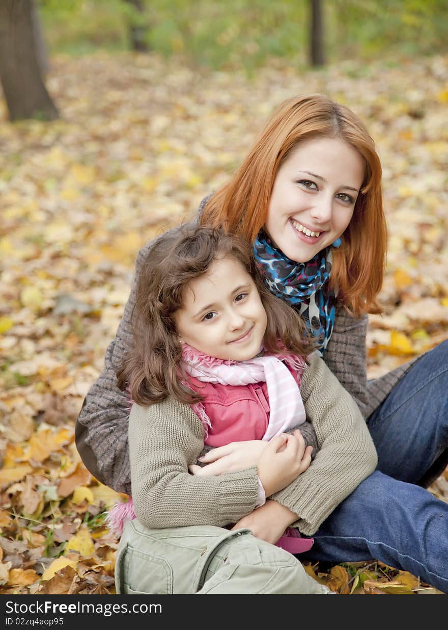 Two sisters sitting on the leafs in the park.