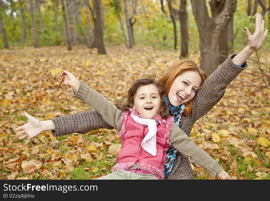 Two sisters sitting on the leafs in the park.