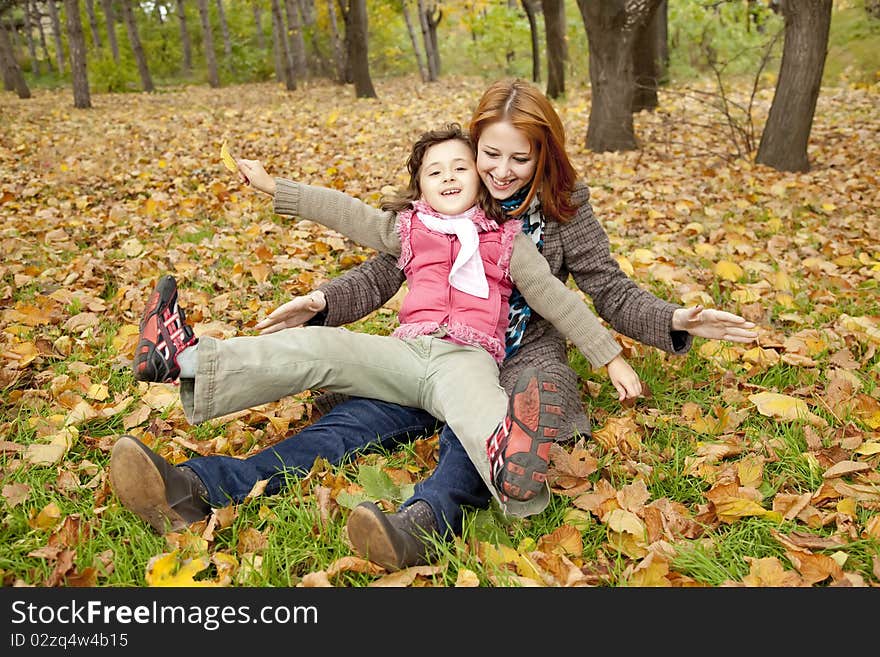 Two sisters sitting on the leafs in the park.