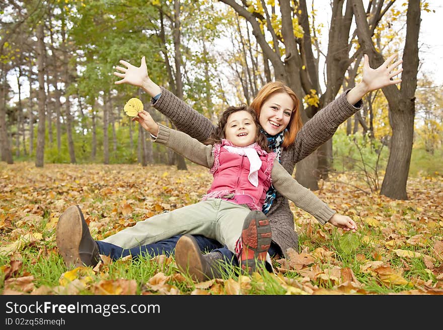 Two sisters sitting on the leafs in the park.