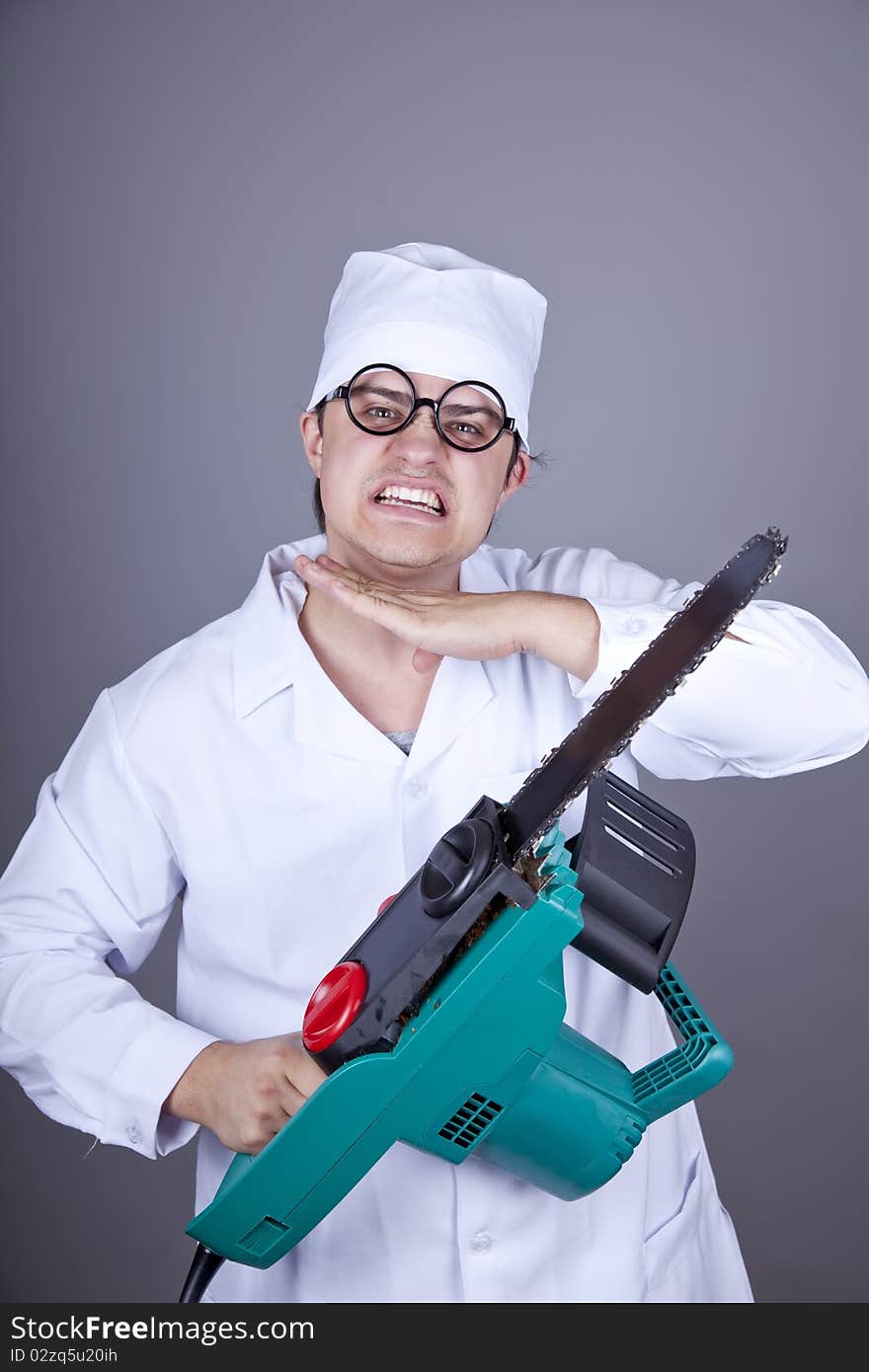 Crazy doctor with portable saw. Studio shot.