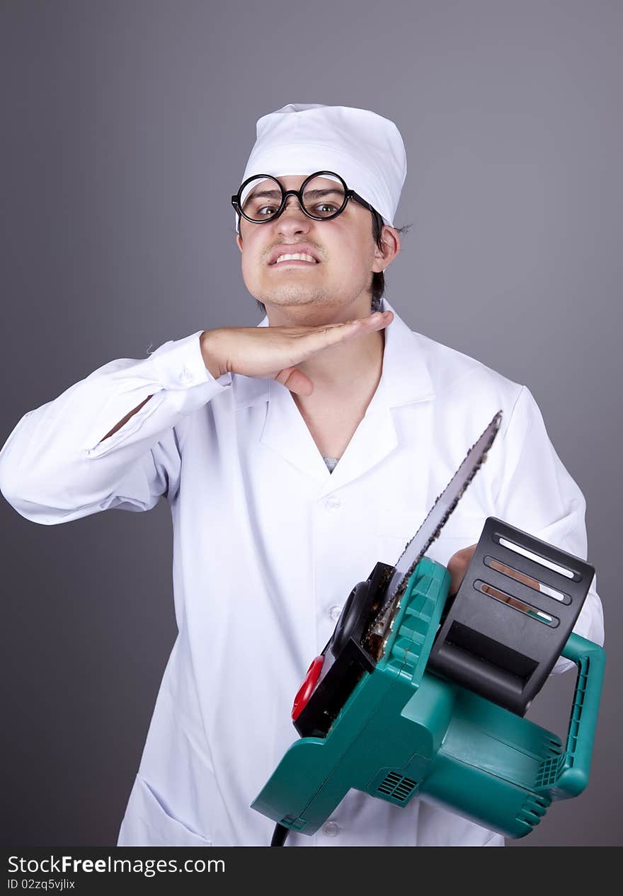 Crazy doctor with portable saw. Studio shot.