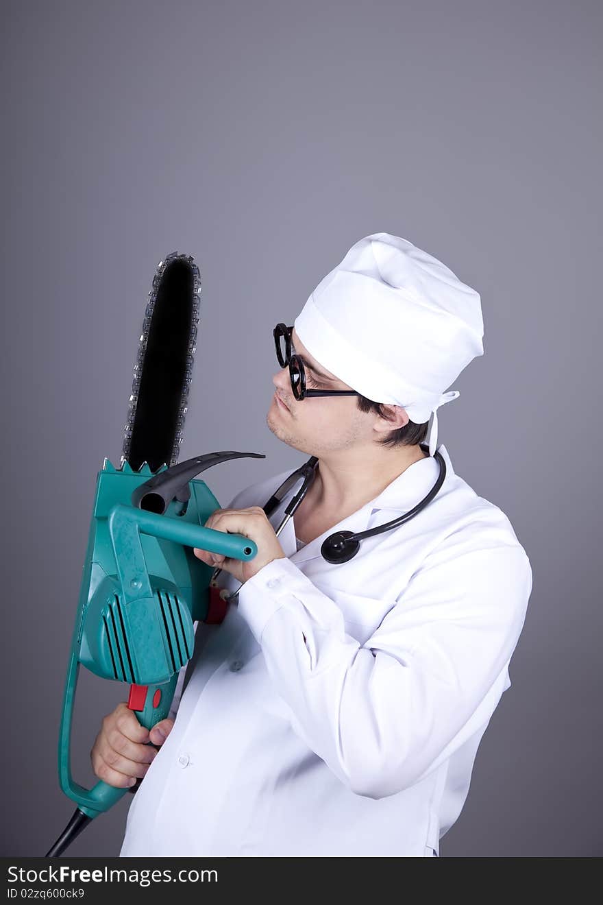 Crazy doctor with portable saw. Studio shot.