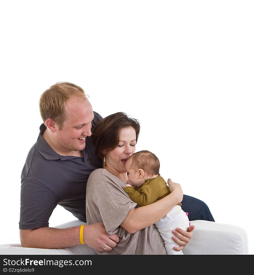 Young happy couple on a couch with their baby over white background. Young happy couple on a couch with their baby over white background.