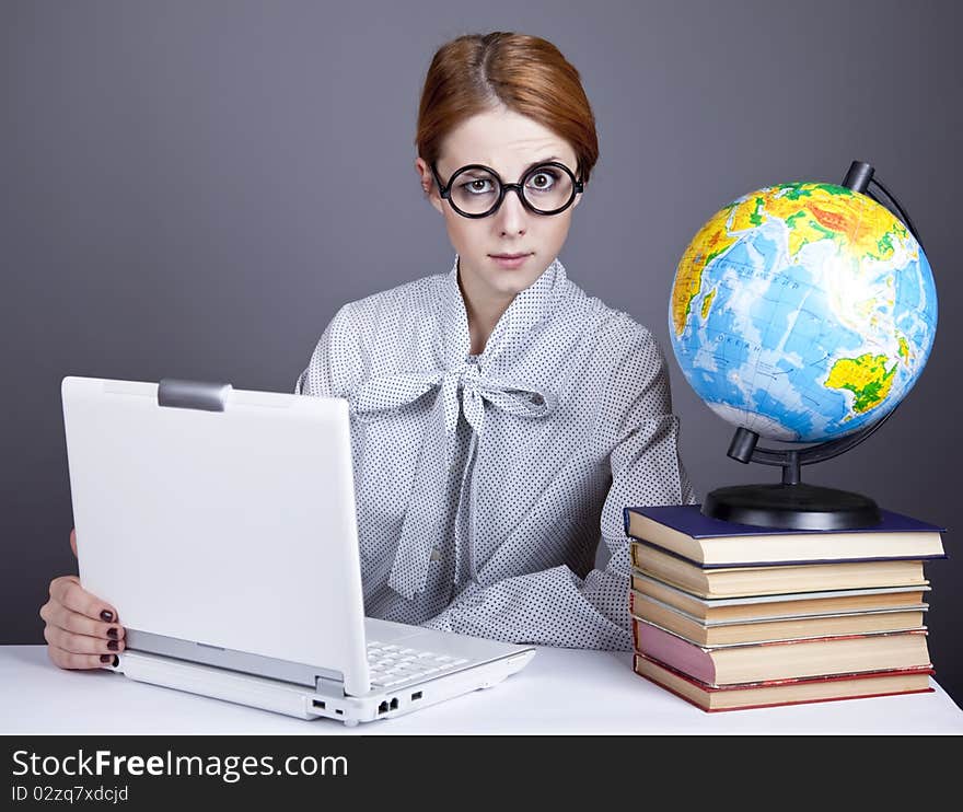 The young teacher in glasses with books, globe and notebook. Studio shot. The young teacher in glasses with books, globe and notebook. Studio shot.