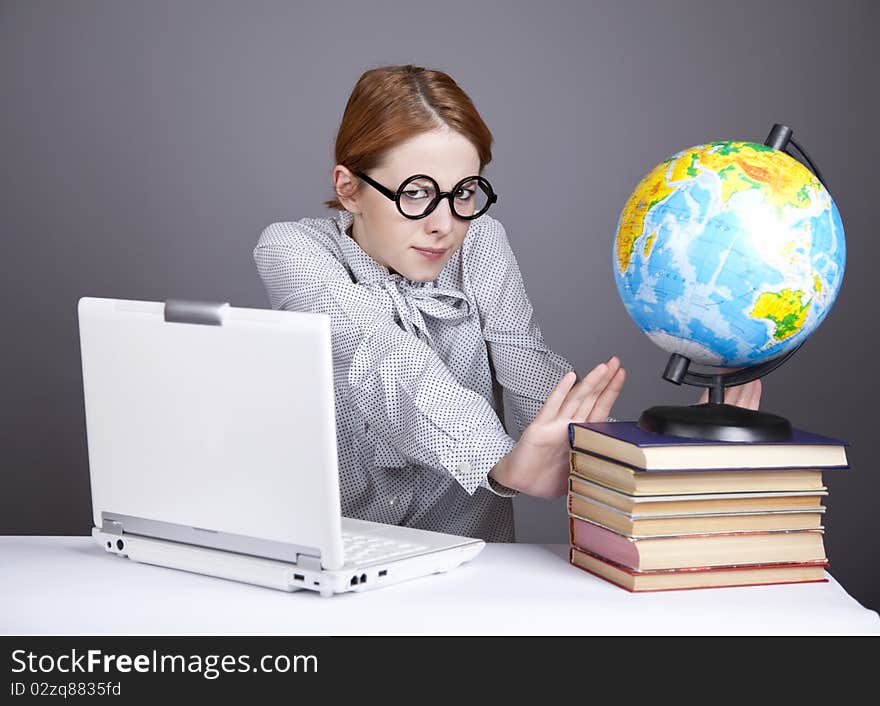 The young teacher in glasses with books, globe and notebook. Studio shot. The young teacher in glasses with books, globe and notebook. Studio shot.