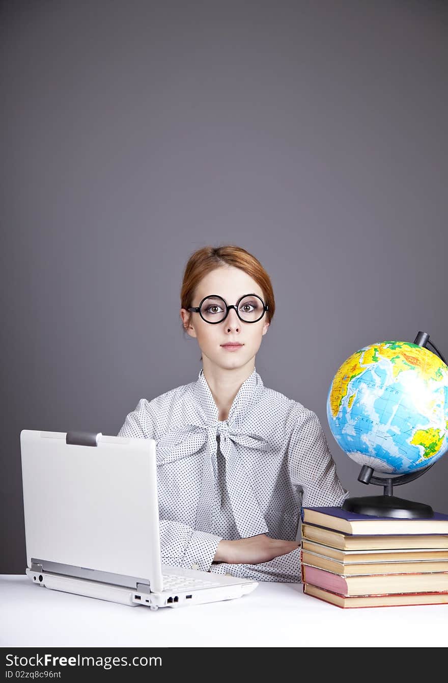 The young teacher in glasses with books, globe and notebook. Studio shot. The young teacher in glasses with books, globe and notebook. Studio shot.