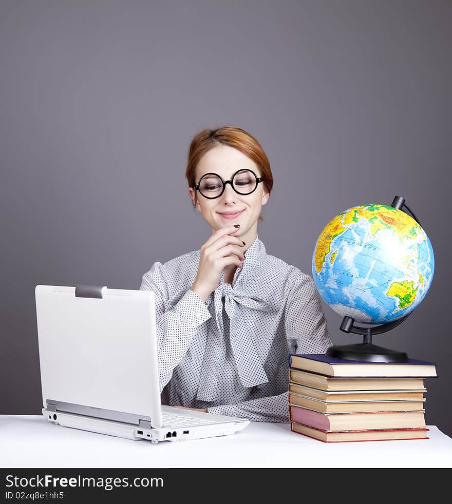 The young teacher in glasses with books, globe and notebook. Studio shot. The young teacher in glasses with books, globe and notebook. Studio shot.