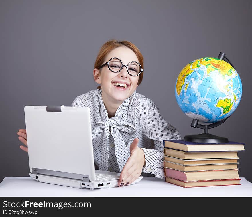 The young teacher in glasses with books, globe and notebook. Studio shot. The young teacher in glasses with books, globe and notebook. Studio shot.