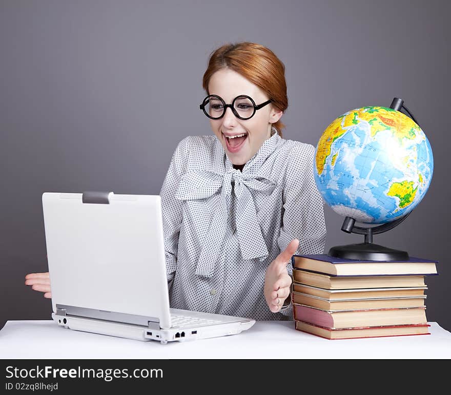 The young teacher in glasses with books, globe and notebook. Studio shot. The young teacher in glasses with books, globe and notebook. Studio shot.