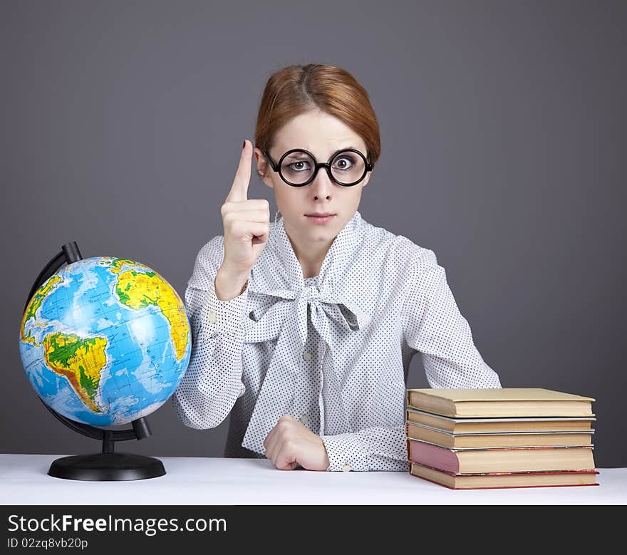 The young teacher in glasses with books and globe. Studio shot.