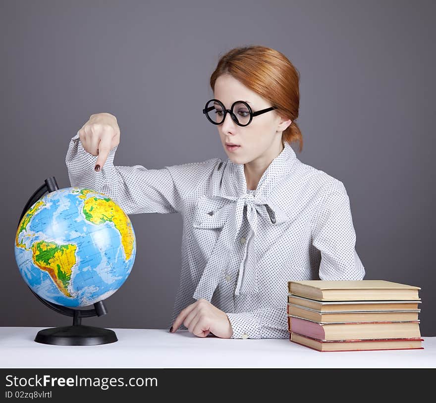 The young teacher in glasses with books and globe. Studio shot.