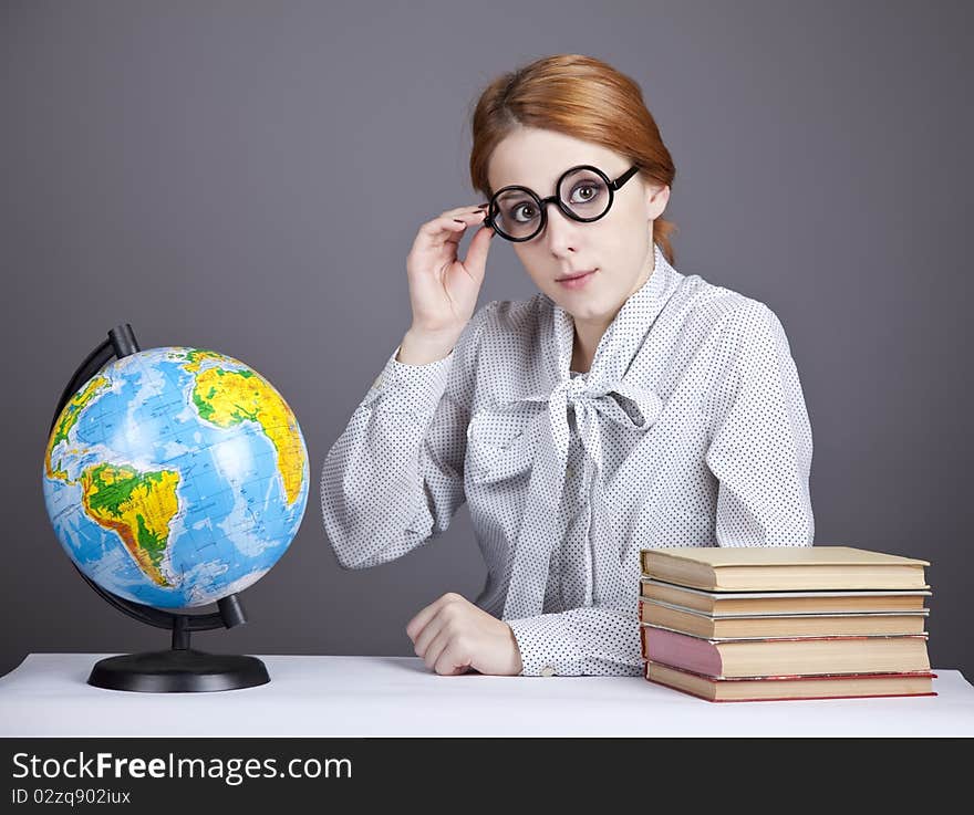 The young teacher in glasses with books and globe. Studio shot.