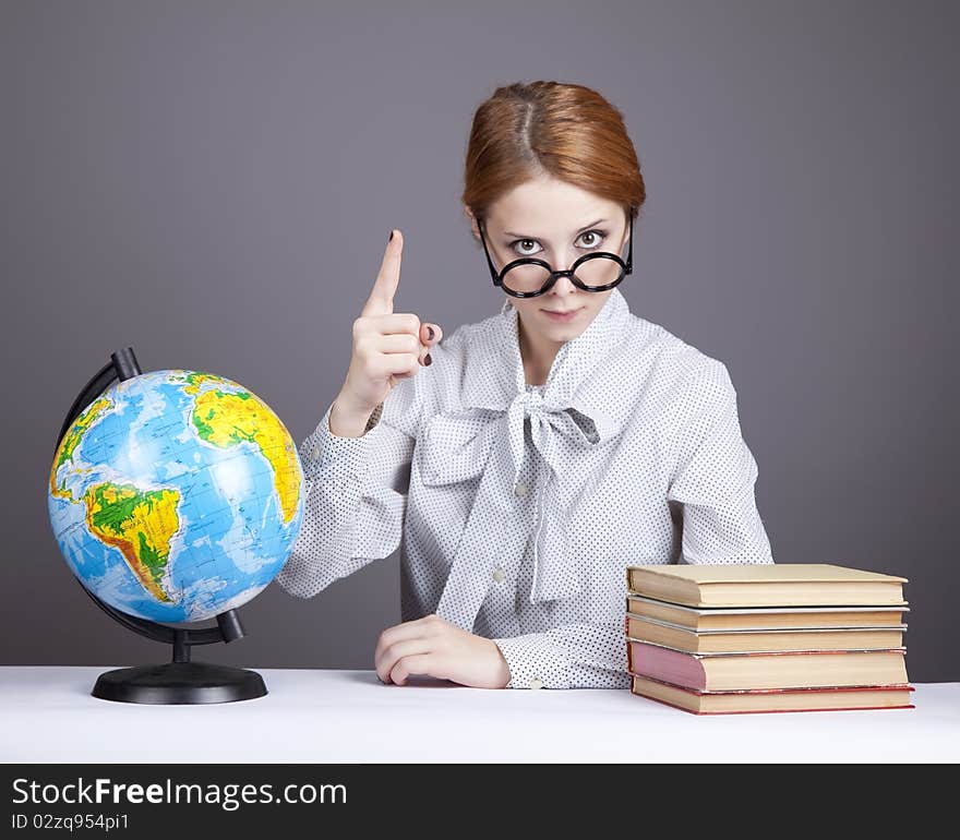 The young teacher in glasses with books and globe. Studio shot.