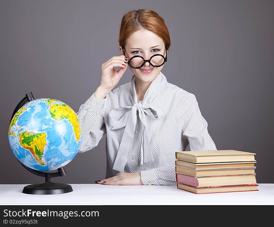 The young teacher in glasses with books and globe. Studio shot.