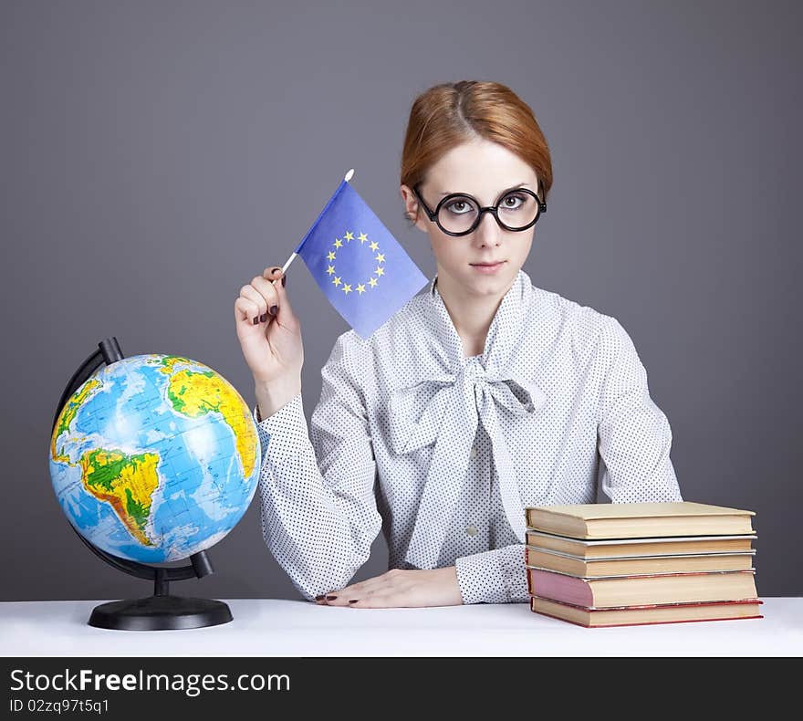 The young teacher in glasses with books and globe. Studio shot.