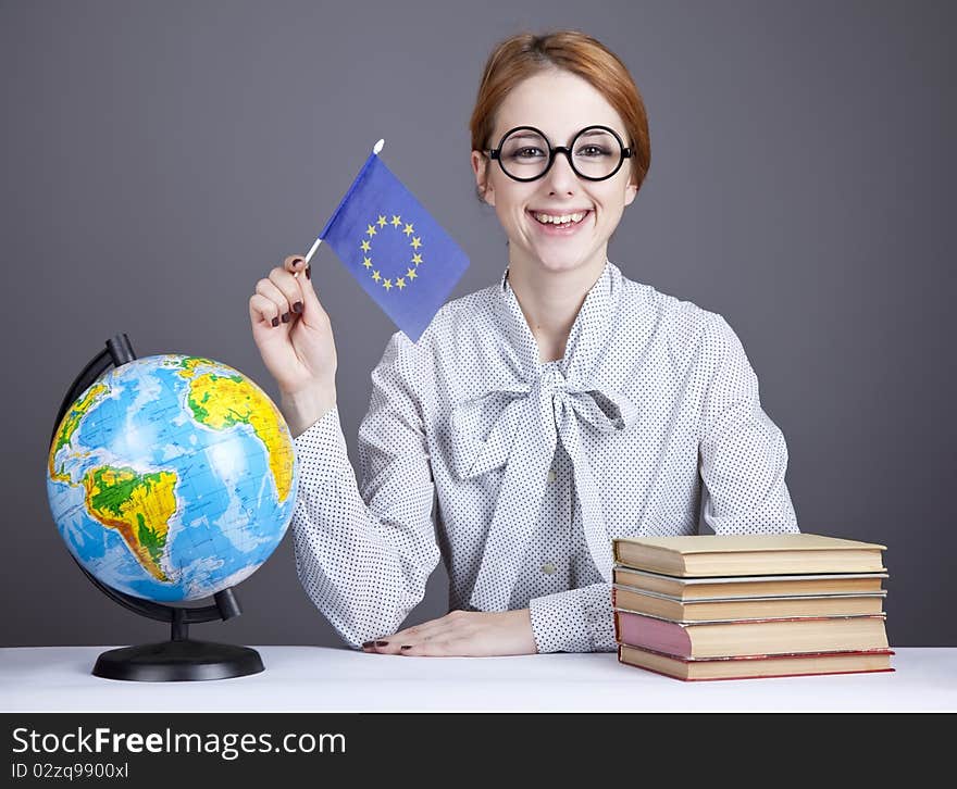 The young teacher in glasses with books and globe. Studio shot.