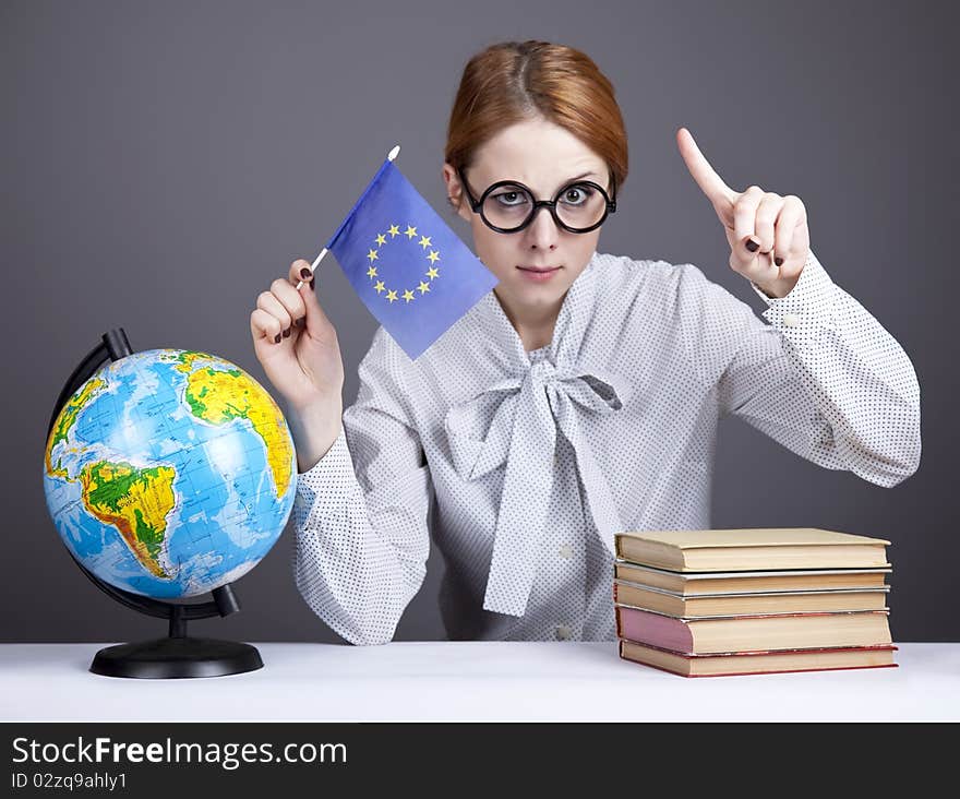 The young teacher in glasses with books and globe. Studio shot.