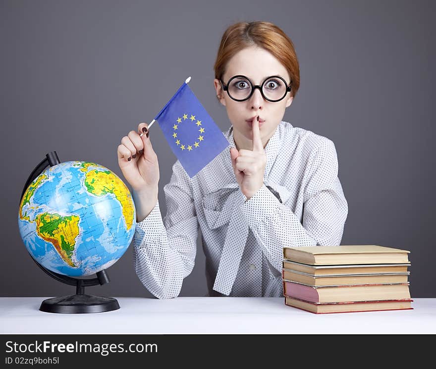 The young teacher in glasses with books and globe. Studio shot.