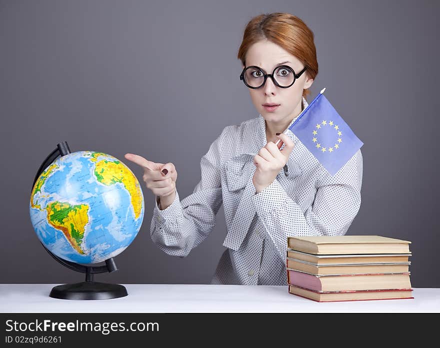 The young teacher in glasses with books and globe. Studio shot.