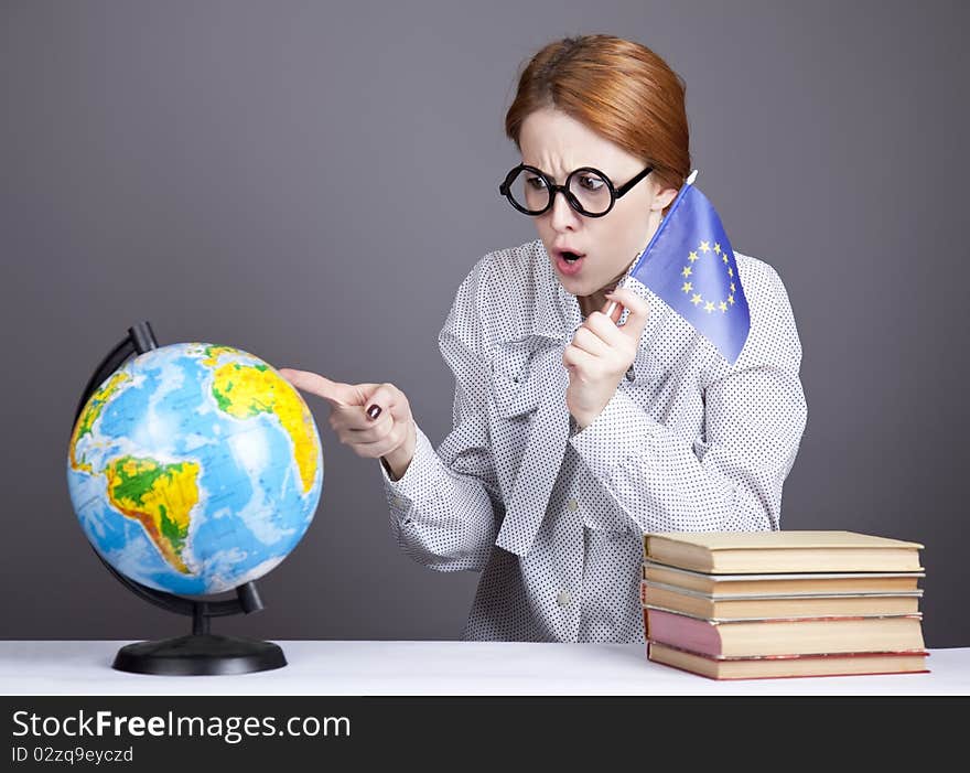 The young teacher in glasses with books and globe. Studio shot.