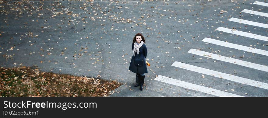 A young girl standing on a road near a pedestrian crossing