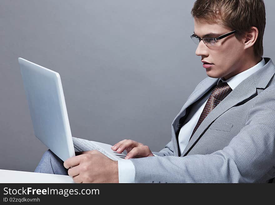 A young man in a suit with a laptop. A young man in a suit with a laptop