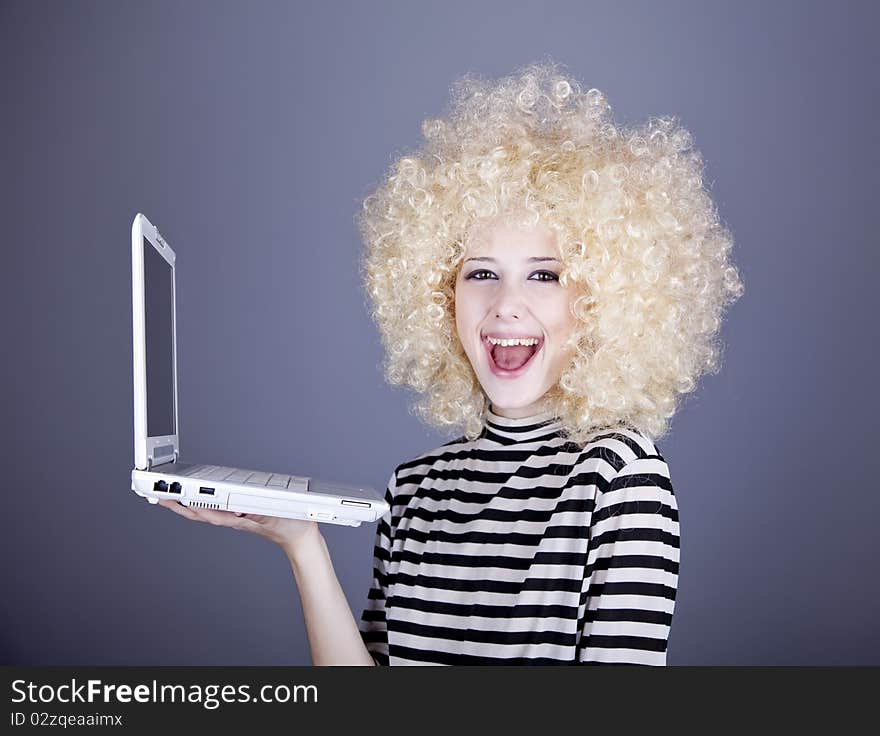 Portrait of funny girl in blonde wig with laptop. Studio shot.