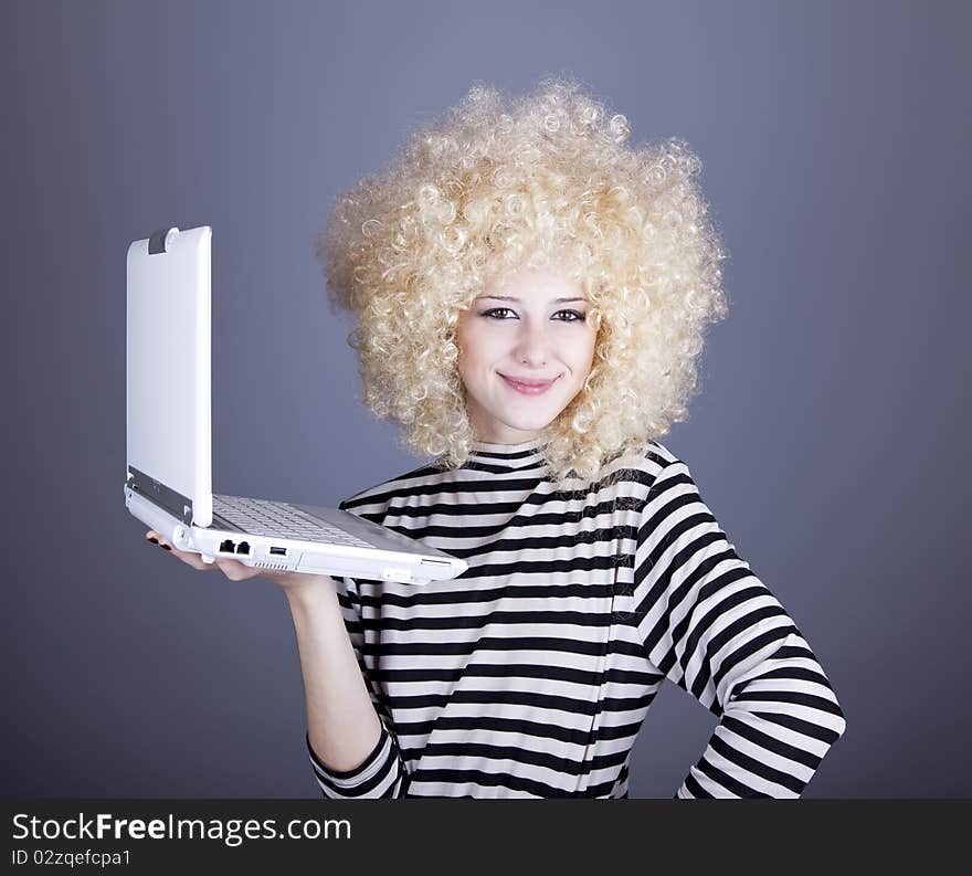 Portrait of funny girl in blonde wig with laptop. Studio shot.