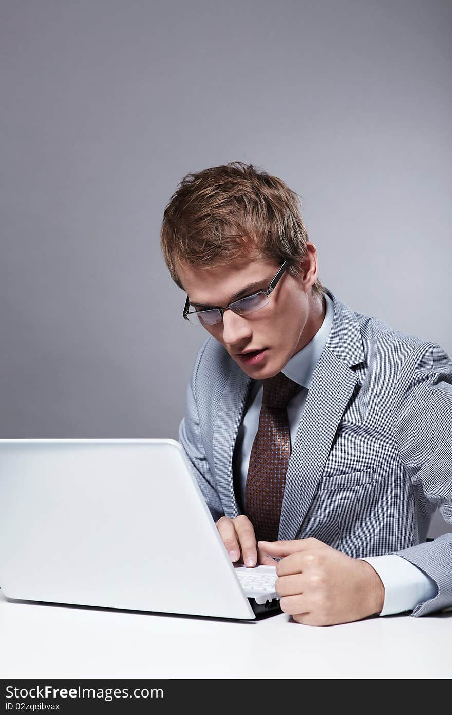 A young man in a suit looking at laptop. A young man in a suit looking at laptop