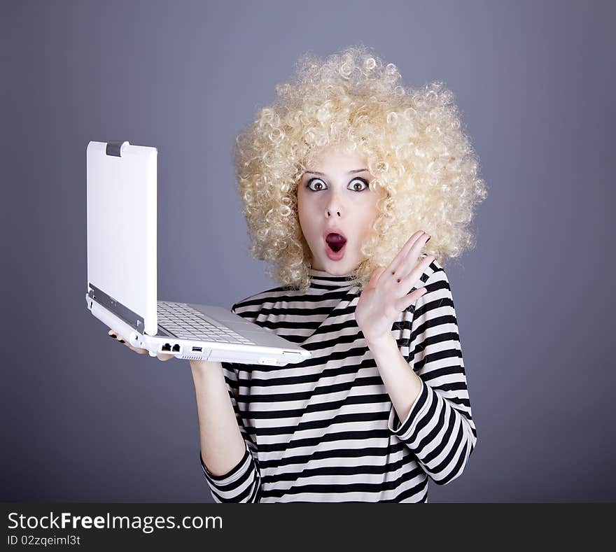 Portrait of funny girl in blonde wig with laptop.