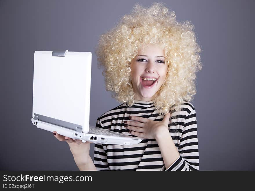 Portrait of funny girl in blonde wig with laptop. Studio shot.