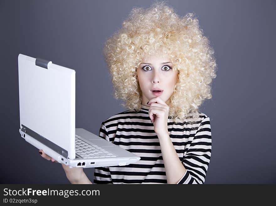 Portrait of funny girl in blonde wig with laptop. Studio shot.