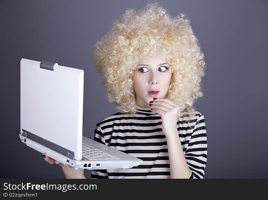 Portrait of funny girl in blonde wig with laptop. Studio shot.