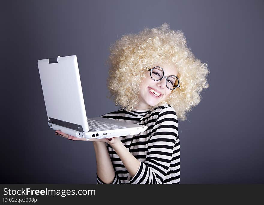 Portrait of funny girl in blonde wig with laptop. Studio shot.