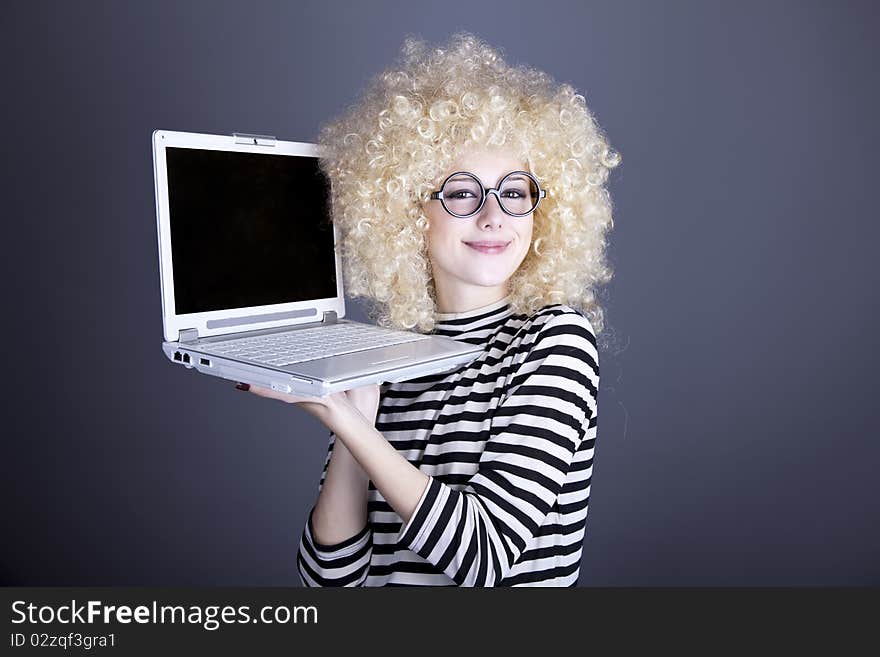 Portrait of funny girl in blonde wig with laptop. Studio shot.