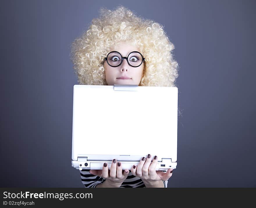 Portrait of funny girl in blonde wig with laptop. Studio shot.